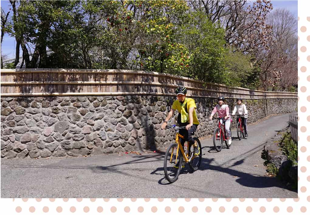 石垣の小道をサイクリングで通る男女3人