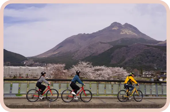 由布岳をバックにサイクリングをする男女3人